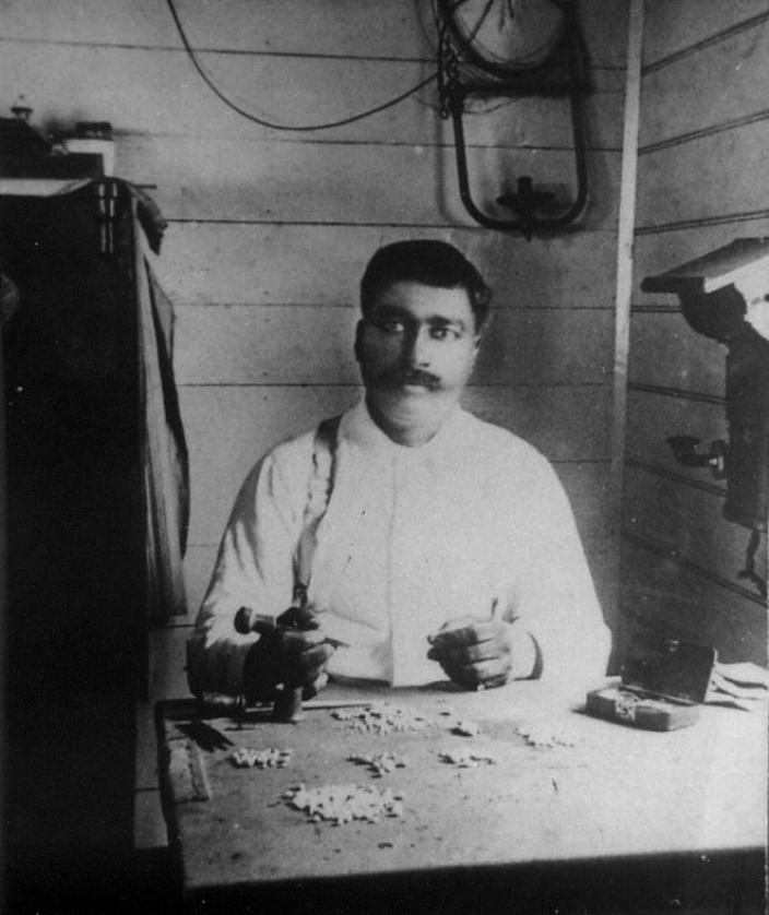 A black and white portrait of a man sitting at a desk. 